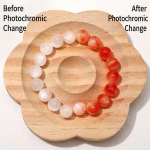 Detail von UV-photochromen Harzperlen, die auf einem Holztablett von Weiß zu Orange wechseln.
