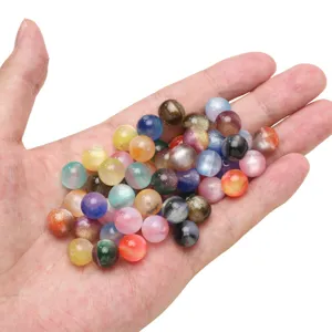 Close-up detail of colorful gradient round beads with gold glitter held in hand for DIY