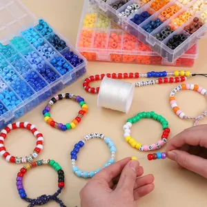 Detailaufnahme von Händen, die bunte Acryl-Tonnenperlen für DIY-Armband auffädeln