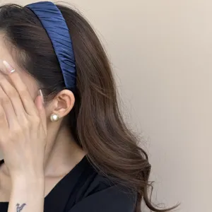 Detailansicht eines eleganten, plissierten, marineblauen Satin-Stirnbands am Model