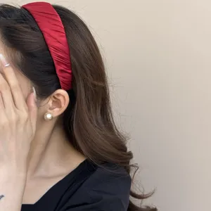 Detailansicht eines roten Satin-Haarbandes mit eleganten Falten bei einem Modell
