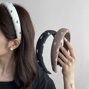 Detailed view of three retro padded headbands with cute bow patterns worn by a model