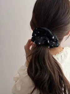 Detailed back view of a vintage black scrunchie with white bow patterns on wavy brown hair