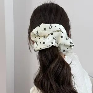 Detailed view of an elegant white printed fabric scrunchie on a brown ponytail.