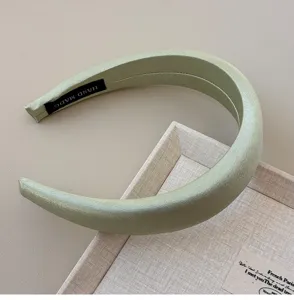 Detail shot of a wide sage green padded headband featuring a silk-like lustrous finish
