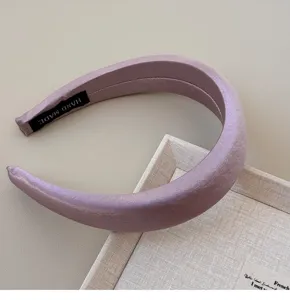 Close-up view of a vintage silken mauve headband with high-gloss finish and handmade label