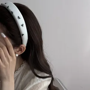 Side view detail of a vintage white padded headband featuring cute black bow prints