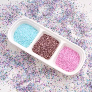 Macro detail of blue purple and pink iridescent crushed glass gravel in a sorting tray