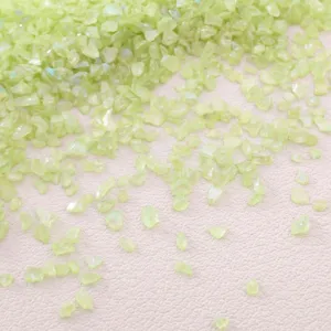 Close-up macro view of iridescent light green crushed glass stones for DIY craft filling