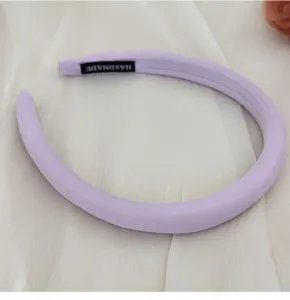 Eleganter violetter Schwamm-Haarreif mit Handmade-Etikett auf weißem Seidenhintergrund
