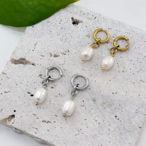 Detail of gold and silver stainless steel hoop earrings with white freshwater pearl drops.