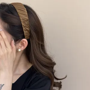 Detailansicht eines plissierten braunen Satin-Haarbandes mit eleganter Stofftextur