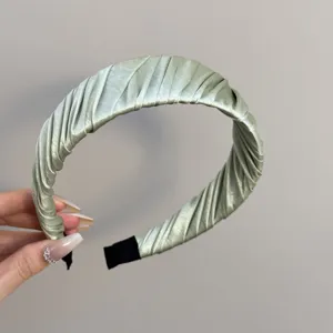Nahaufnahme des eleganten, gefalteten Satin-Stirnbands in Salbeigrün mit hochwertiger Textur