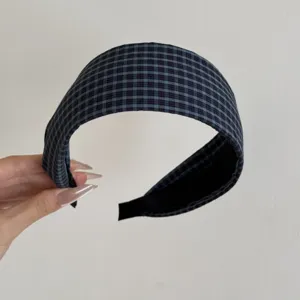 Vue détaillée d'un serre-tête large à carreaux bleus et noirs en tissu texturé