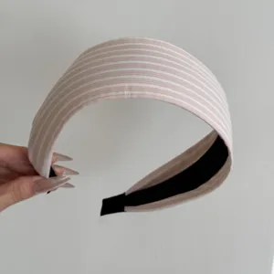 Gros plan d'un serre-tête large à rayures roses et blanches élégant avec doublure noire.