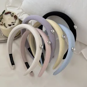 Detailed view of textured fabric headbands with heart-shaped pearl ornaments in various colors