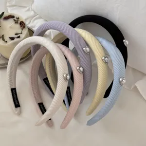 Set of various pastel corduroy headbands featuring decorative heart-shaped pearls.