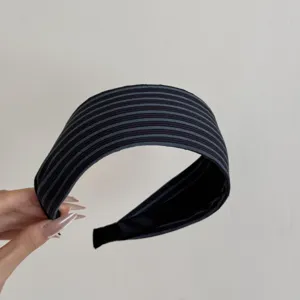 Vue détaillée de la texture du tissu rayé bleu marine sur ce bandeau à larges bords élégant