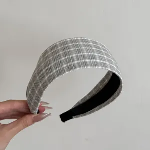 Vue détaillée d'un bandeau en tissu à larges bords à carreaux gris élégant tenu à la main.
