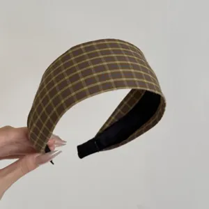 Gros plan d'un large serre-tête de style coréen avec un motif à carreaux marron et vert.