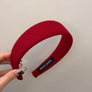Close-up of red plaid wool headband with woven texture and handmade label