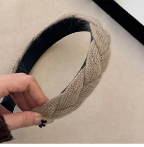 Detailopname van een kaki gebreide gevlochten haarband met dikke wollen textuurdetails
