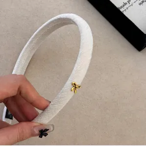 Macro di un elegante cerchietto in velluto bianco con un delicato fiocchetto dorato chic.