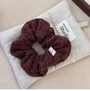 Close-up macro view of a dark burgundy felt hair scrunchie showing soft plush texture