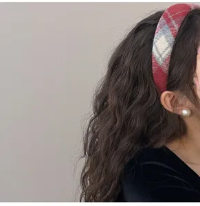 Side view showing a red plaid woolen headband on long wavy hair for a chic look.