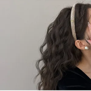 Dettaglio di un elegante cerchietto stretto in velluto con fiocchetto dorato su capelli