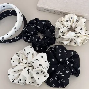 Detailed view of elegant black and white bow print scrunchies and headband set.