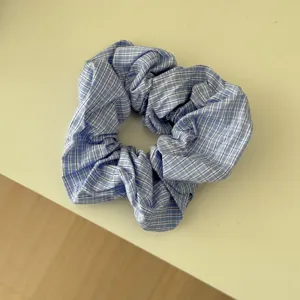 Dettaglio ravvicinato di uno scrunchie a scacchi blu e bianchi con morbida trama di tessuto