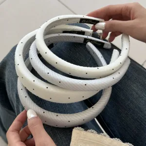 Detailaufnahme eleganter weiß gepolsterter Haarbänder mit schwarzen Punkten und Textur