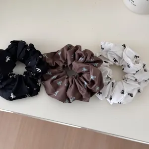 Detail view of three stylish bow-patterned scrunchies in black, brown, and white colors