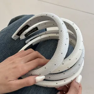 Nahaufnahme von weißen Stoffhaarbändern mit schwarzen Punkten und französischem Design.