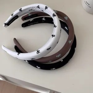 Close-up of three retro fabric headbands in white, brown, and black with cute bow patterns
