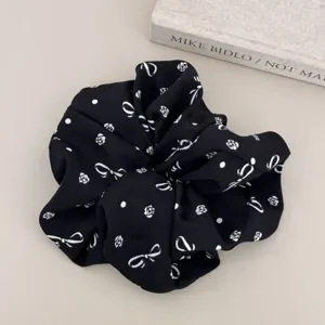 Detailed macro view of a stylish black scrunchie featuring white bow and floral prints