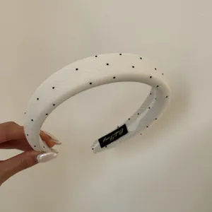 Detailaufnahme eines weißen Retro-Haarbandes mit schwarzen Polka-Dots Design
