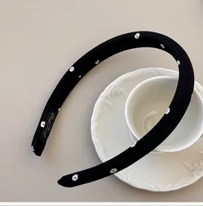 Close-up of black padded sponge headband with delicate white floral pattern motifs