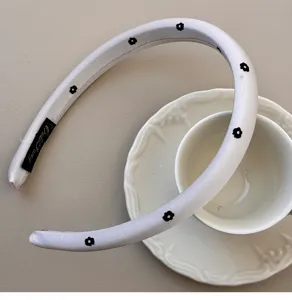 Close-up of padded white headband with black floral pattern on a ceramic cup