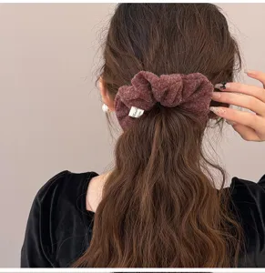 Back view of a burgundy felt scrunchie on brown wavy hair showing a soft fuzzy texture
