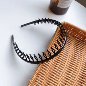Detailed view of a flexible black plastic headband with long teeth on a woven tray