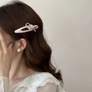 Primo piano di un fermaglio per capelli con fiocco rosa su capelli castani ondulati