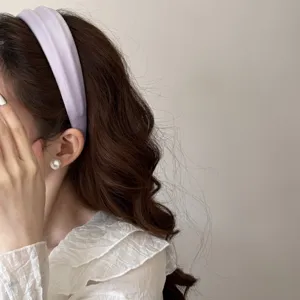 Side view of a lavender high-cranial padded headband worn on wavy brown hair.