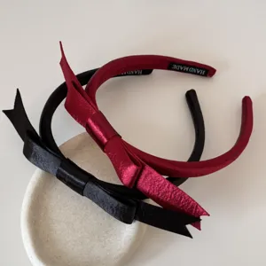 Nahaufnahme eleganter Satin-Haarreifen mit Schleife in klassischem Schwarz und Weinrot.
