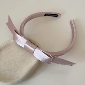 Detailansicht eines süßen rosa Haarreifs mit Satin-Schleife auf einer Stein-Deko