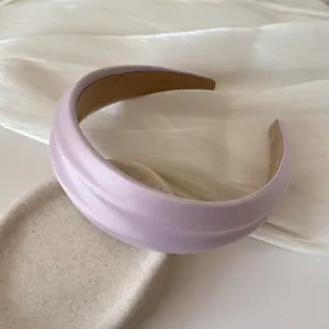 Detail of lavender French style padded headband with silk texture on beige ceramic tray