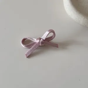 Dettaglio ravvicinato di un fiocco in nastro di raso rosa antico per capelli stile balletto