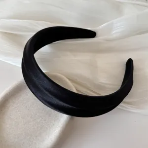 Close-up of elegant black satin French high-top wide headband on textured background