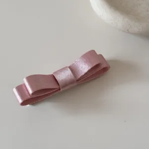 Dettaglio di un accessorio a fiocco in nastro di raso rosa a doppio strato liscio